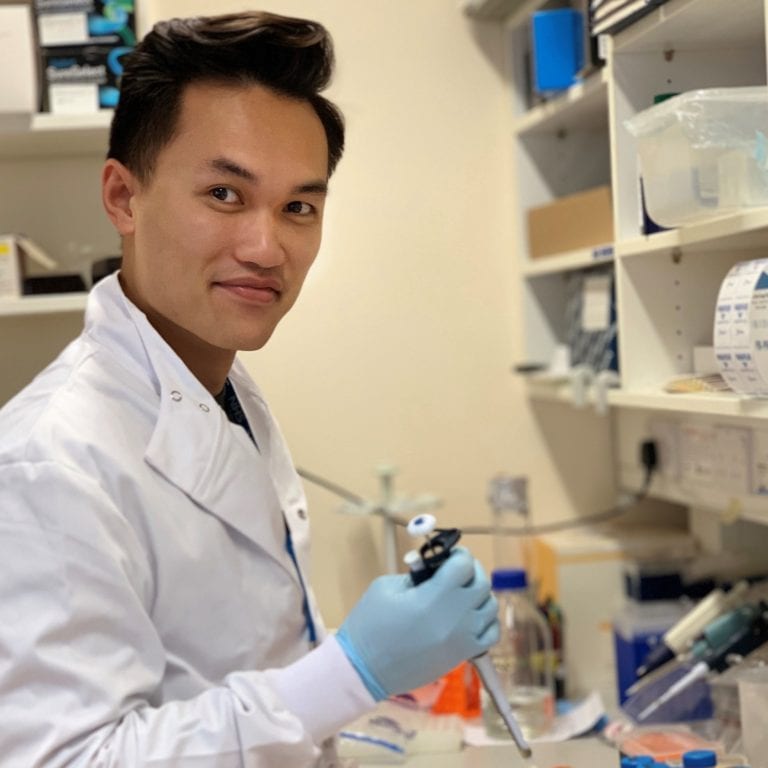 Spencer Tong in a white coat as he works in a research lab
