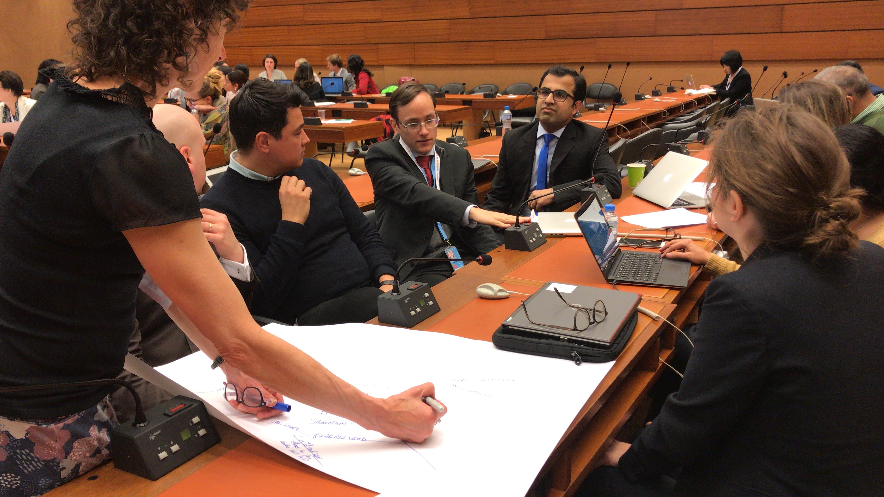 Mark Graham chats with colleagues at a long conference table during a research workshop in Geneva