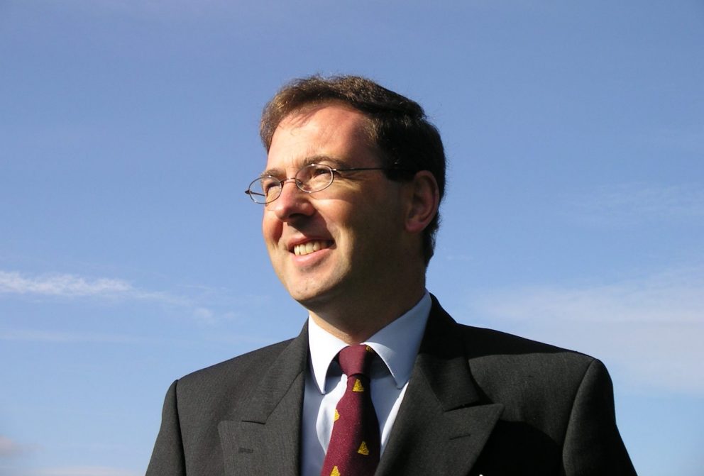 Charles Barclay picture in suit and tie in profile outside with blue sky behind