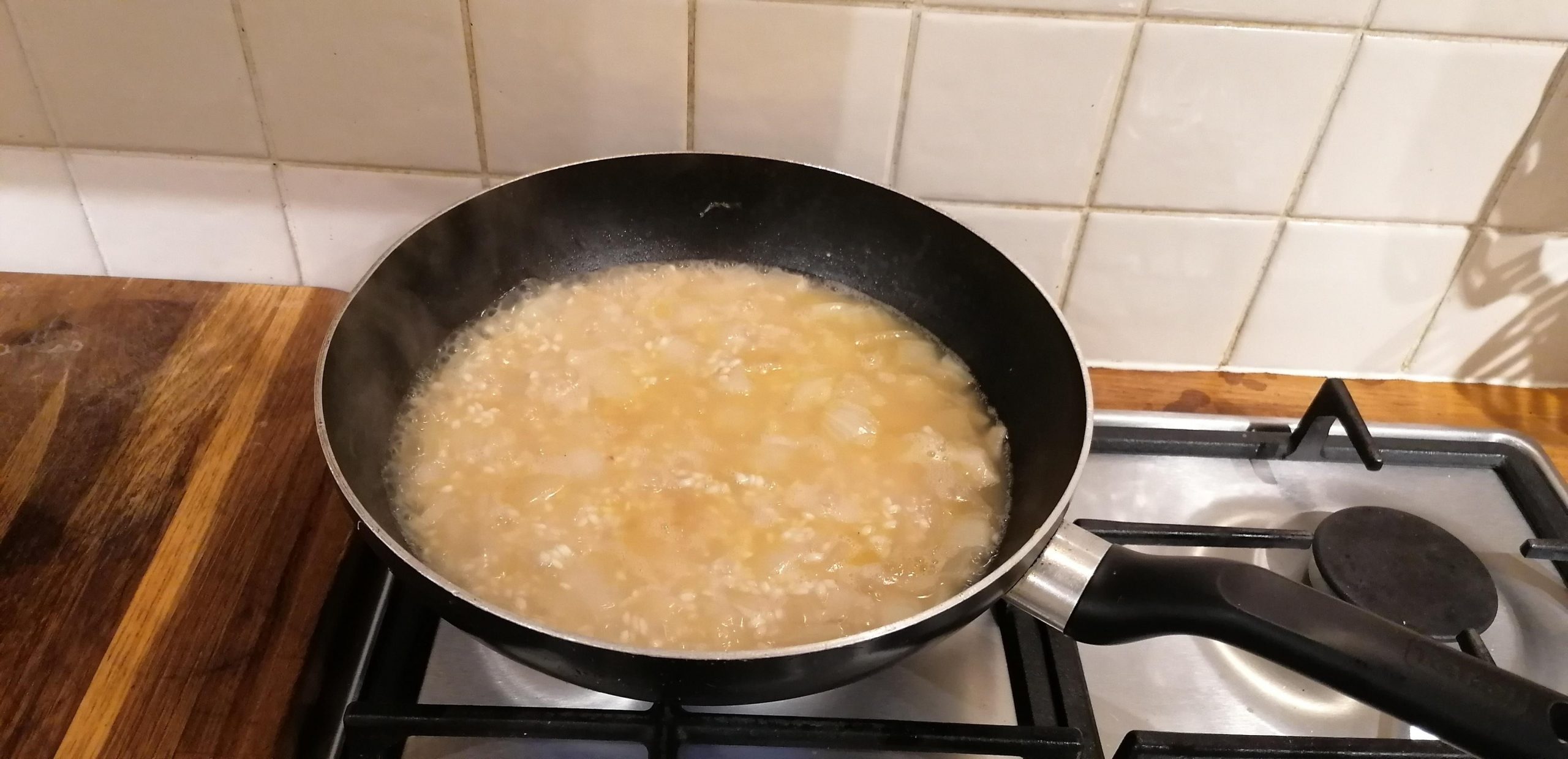 A bubbling pan of chopped onion and onion simmering i n vegetable stock