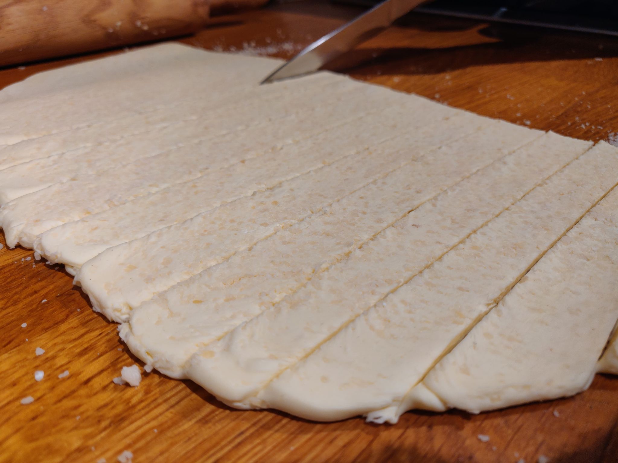 Shortcrust pastry rolled out on a kitchen table ready to be cut into cheese straws