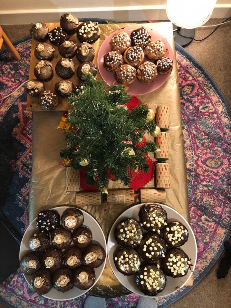 A table covered in a gold tablecloth laden with freshly-baked Christmas cakes and desserts