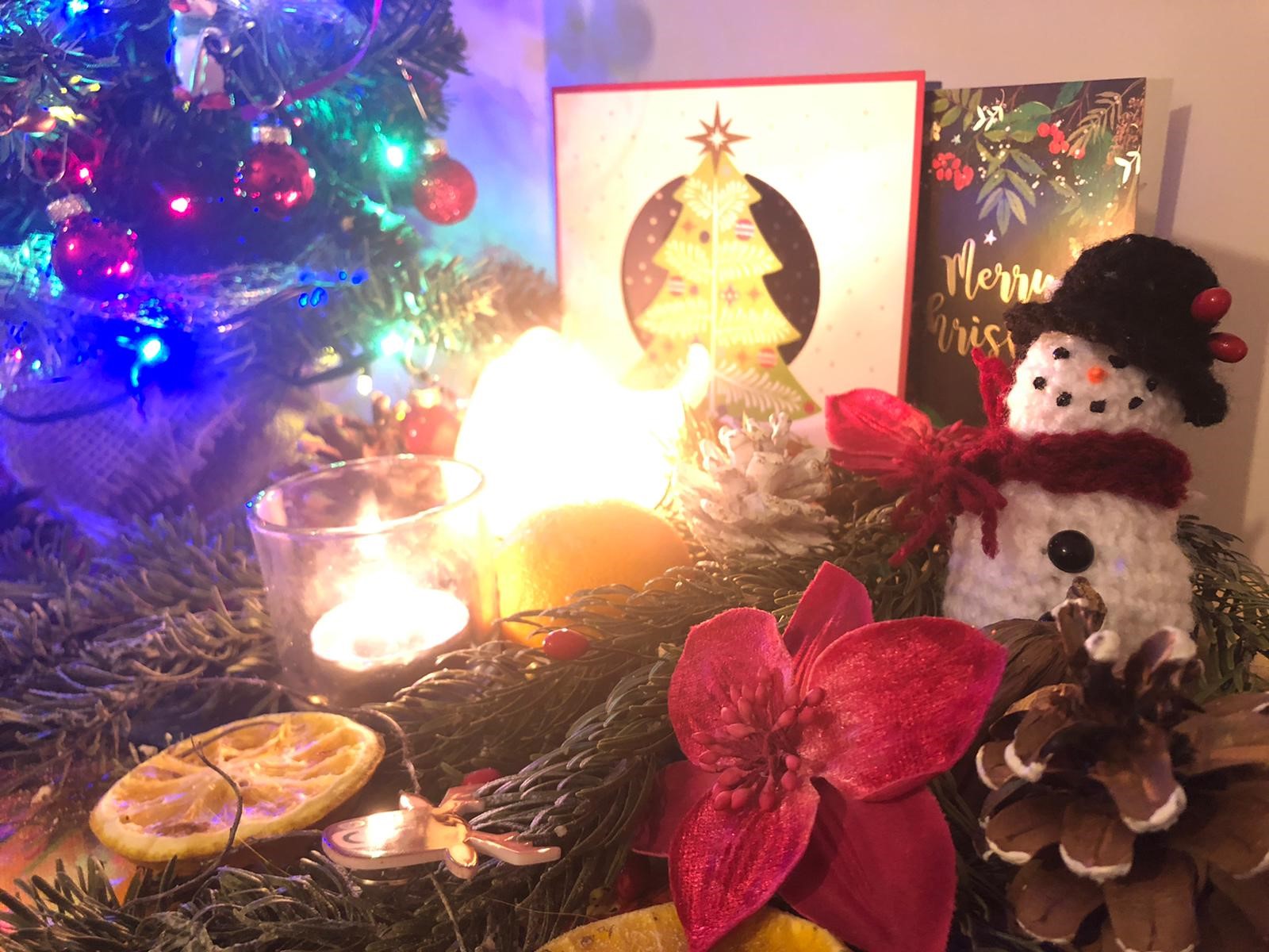 A photograph of a cuddly snowman toy underneath a Christmas tree