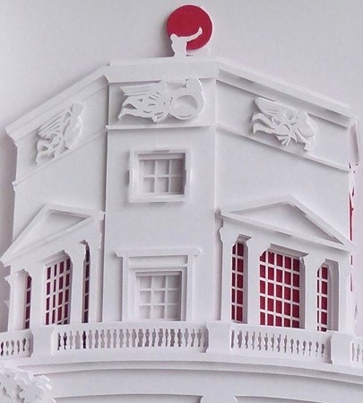A white papercut of the Radcliffe Observatory with red detailing in the windows and globe