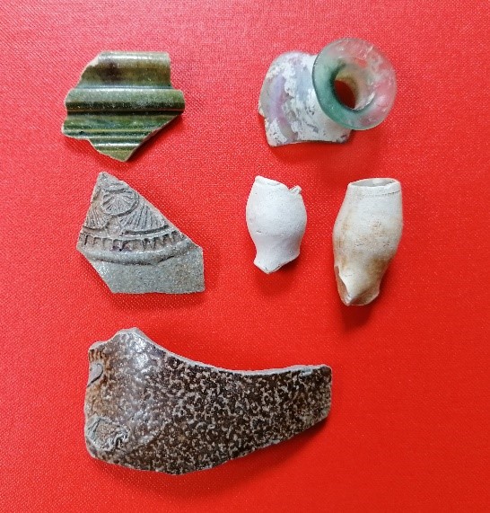 Pottery and clay artifacts displayed on a red cloth