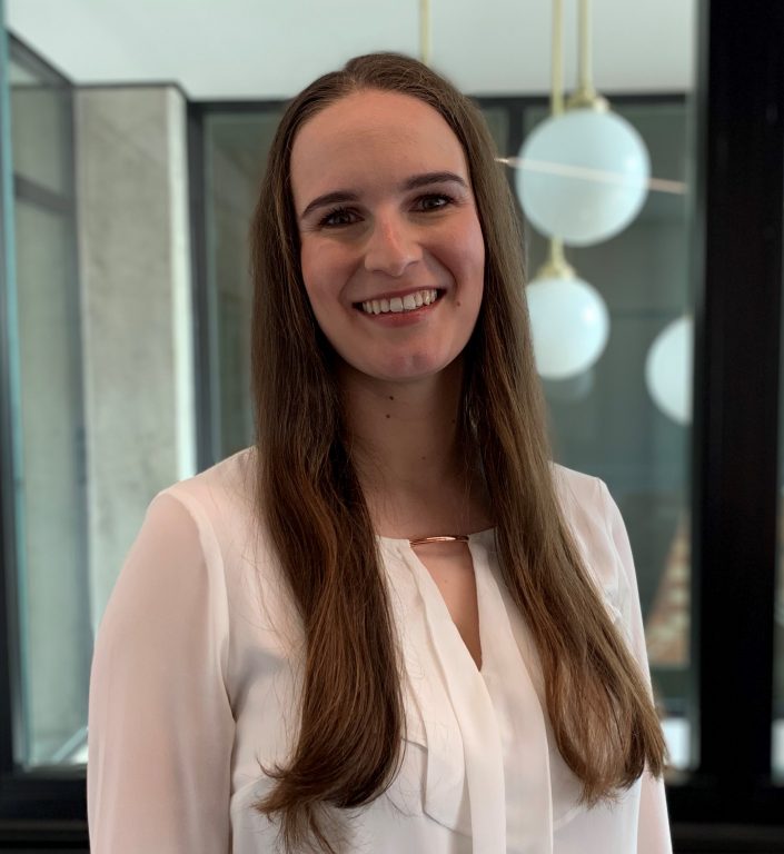 Dr Cervantée Wild portrait in white top with glass and lamps behind