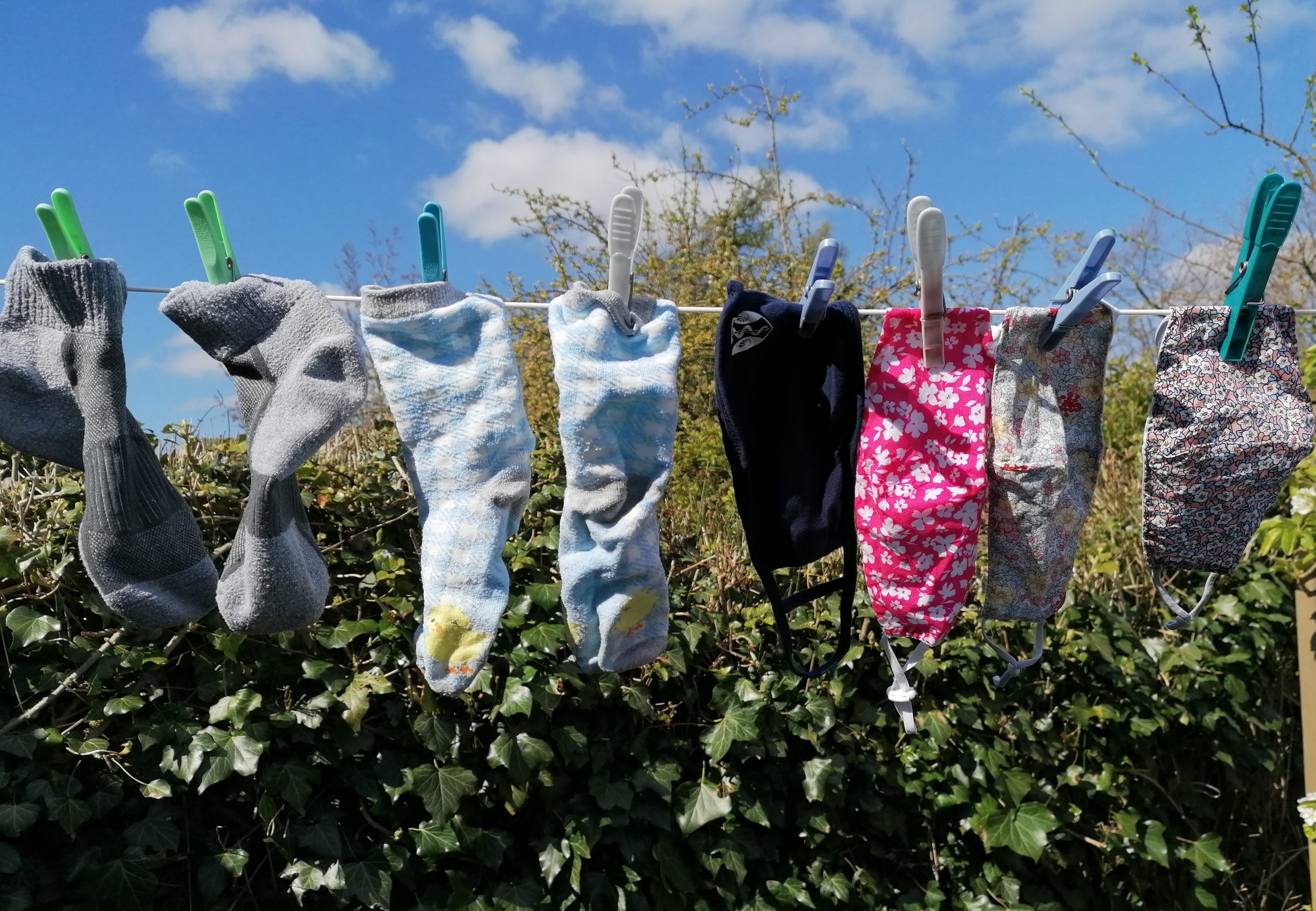 A washing line containing colourful face masks interwined with socks