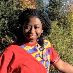 Josephine Agyeman-Duah stood in front of a group of trees, hair pulled back wearing a red outfit