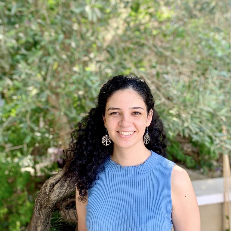 Lamma Mansour wearing a blue top stood in front of a tree