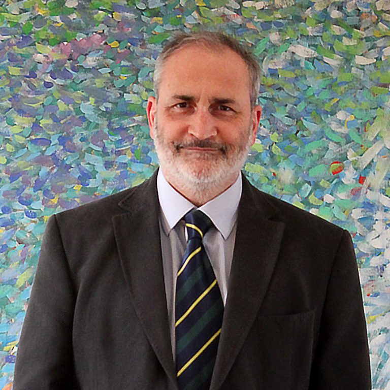 Laurence Leaver In jacket and tie in front of abstract painting in green and blue with bits of red