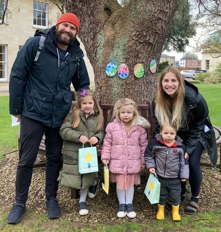 A family in gardens with tree decorated for easter behind