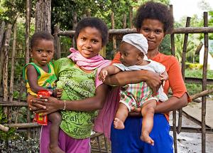 Two women smile as they hold their young children on their hips