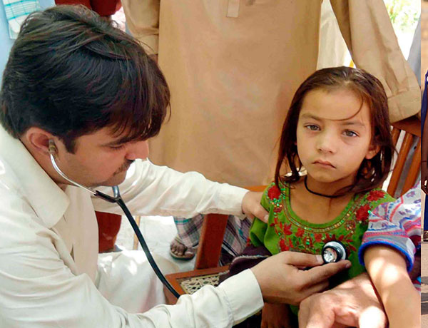 A doctor holds a stethoscope as he examines a young patient