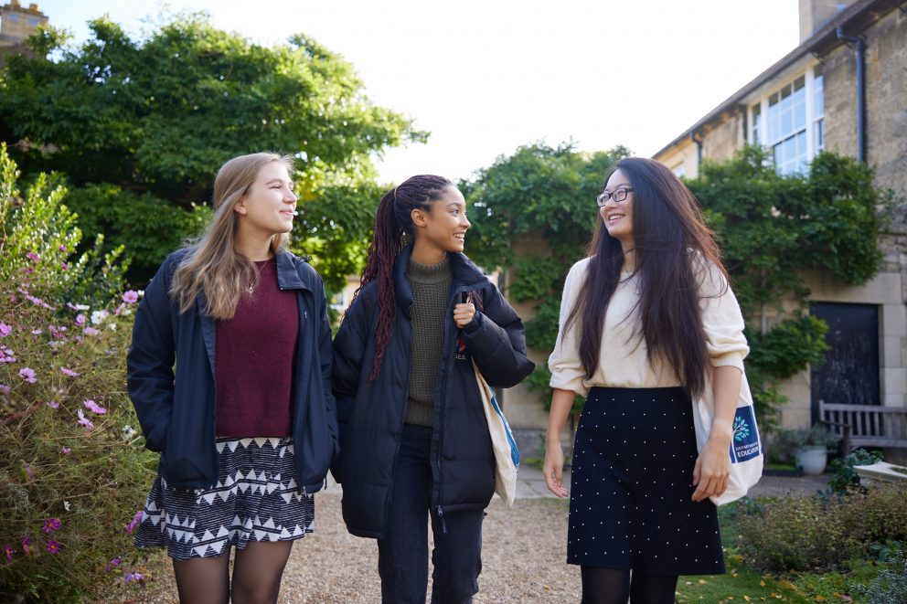 Three students walking through Observatory gardens smiling