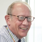 Paul Corris Headshot Looking Over Right Shoulder Smiling In Shirt And Tie