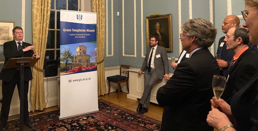 Principal Sir Michael Dixon Welcoming Guests At Lectern With Alumni Banner To Side In Grand Room