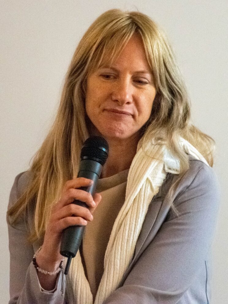 Rosalind Watts Speaking into handheld microphone