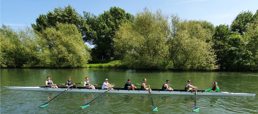 8 rowers and cox in boat from side on with blue and green blades out