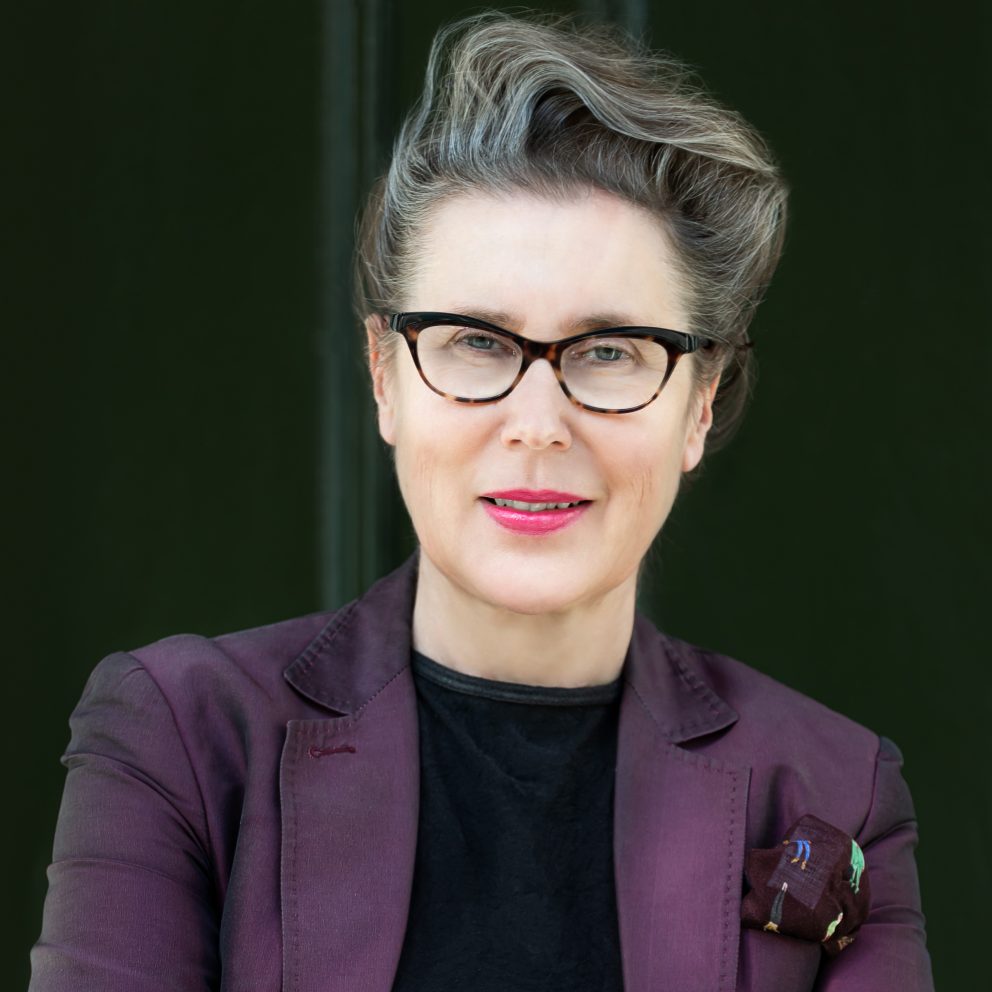 Anne Marie Rafferty Profile Pic In Purple Jacket With Dark Background