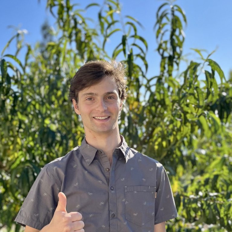 Isaac Rankin with thumb up in front of a green tree with blue skies