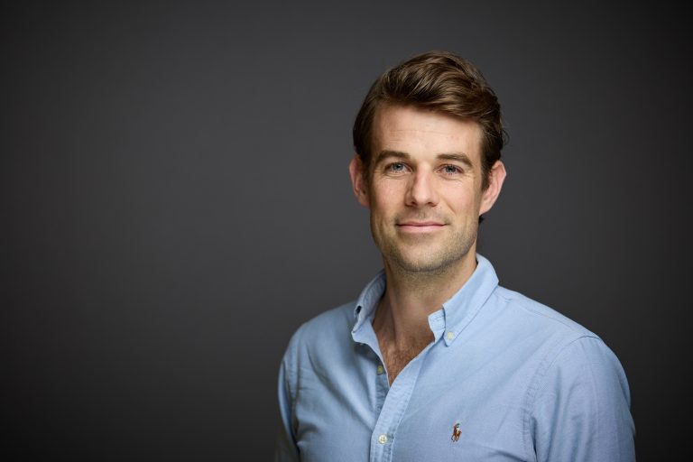 Ludo Van Hillegondsberg wearing blue shirt in front of grey background