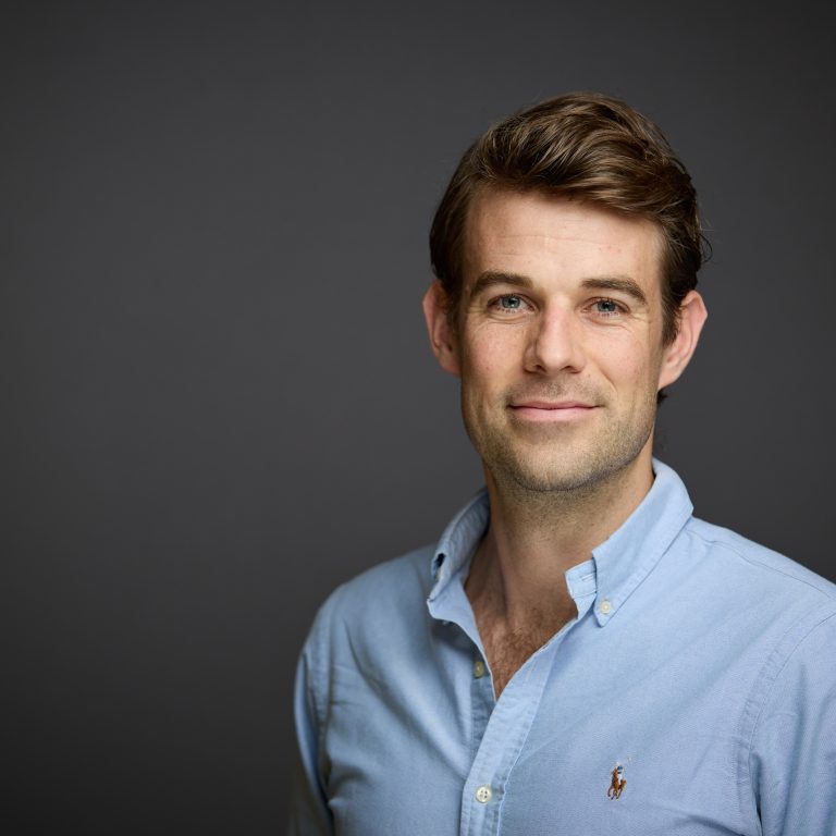 Ludo Van Hillegondsberg wearing blue shirt in front of grey background