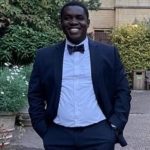 Rudolph Okai In Suit And Bow Tie Outside