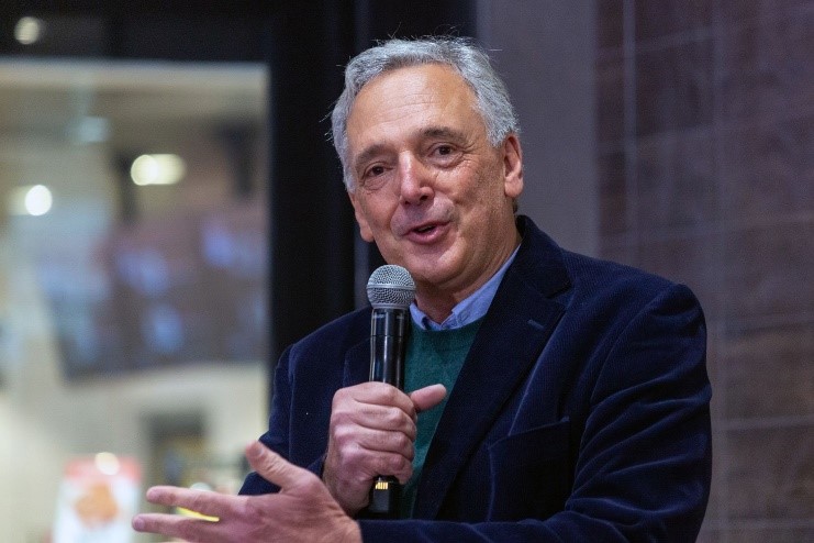 Gareth Ackerman holding microphone and gesturing with one hand