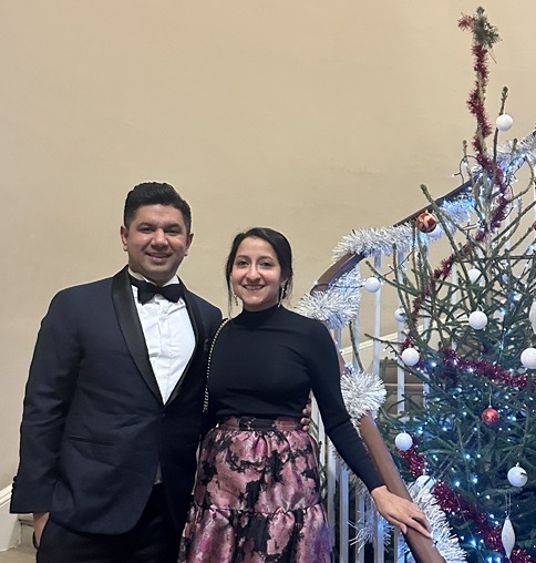 Pratik Gidwani And Sarita Kambhampati On Stairs In Observatory With Christmas Tree To Right