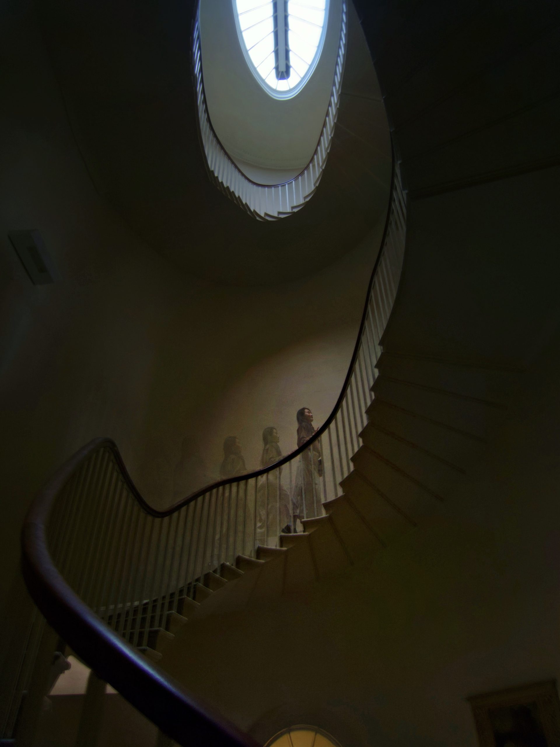 A figure walking up a spiral staircase 