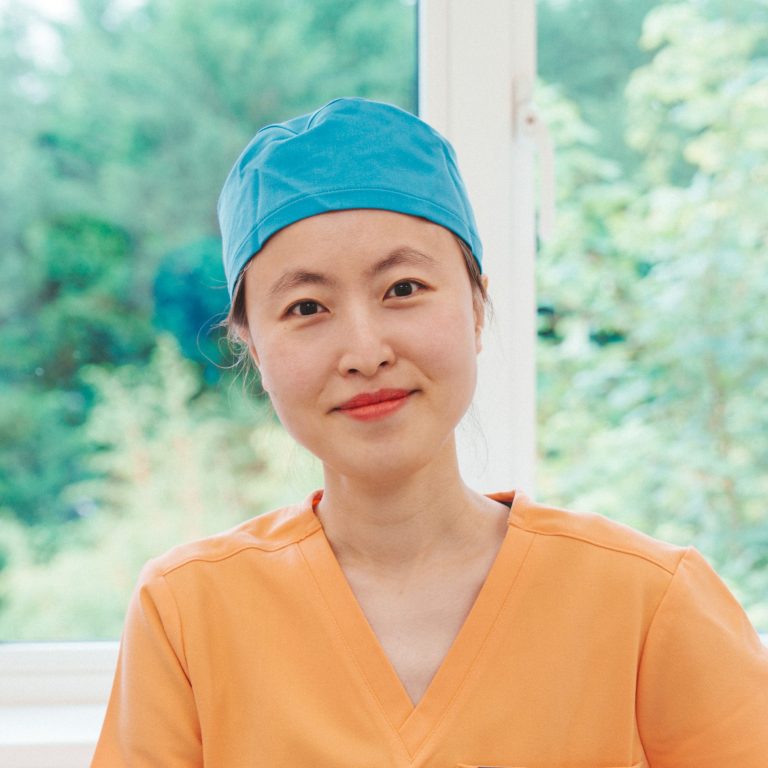Bosun Hong wearing orange scrubs and blue surgical hat