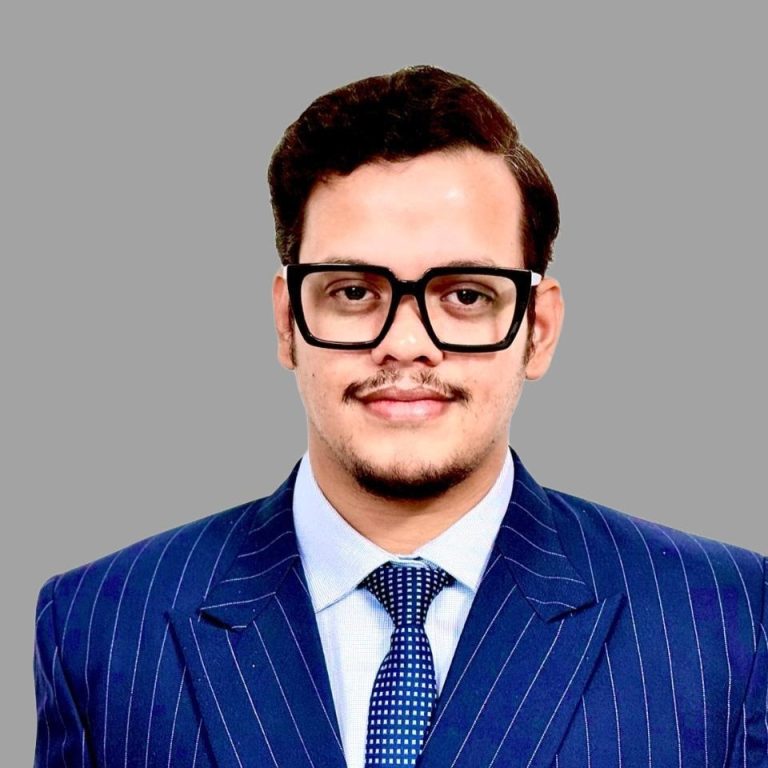 Pulkit Mishra wearing blue pin stripped suit, white shirt, blue tie and glasses.