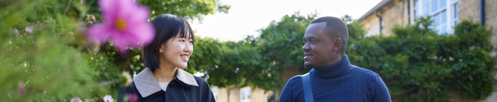 Two students walking and talking in a garden