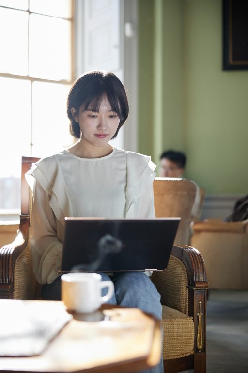 A student sitting at a laptop in a sunny room