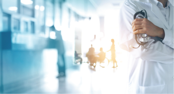 Hospital Setting With Person Holding Stethoscope In Foreground