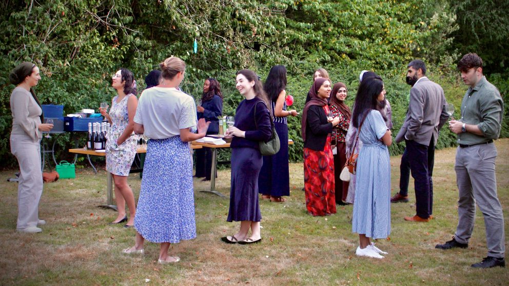 People gathered socialising, standing up in garden