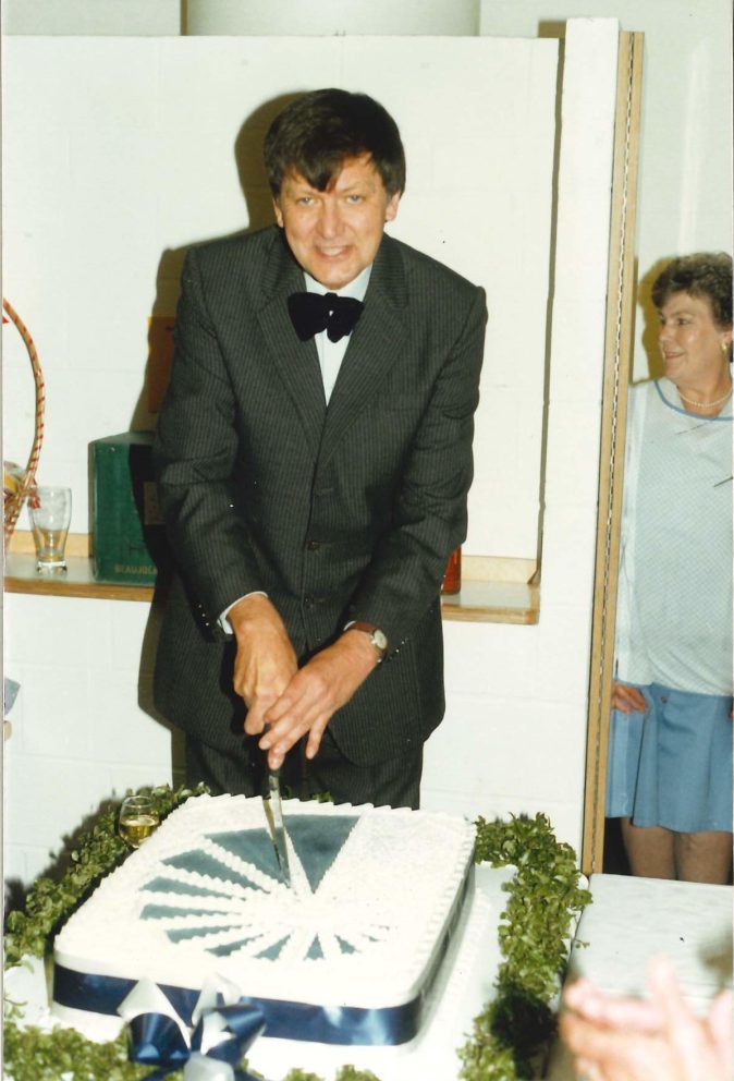Bill Impey cutting cake with nautilus shell on it in bow tie