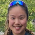 Michelle Yeung Smiling On Balcony By River In Green Templeton Boat Club Shirt